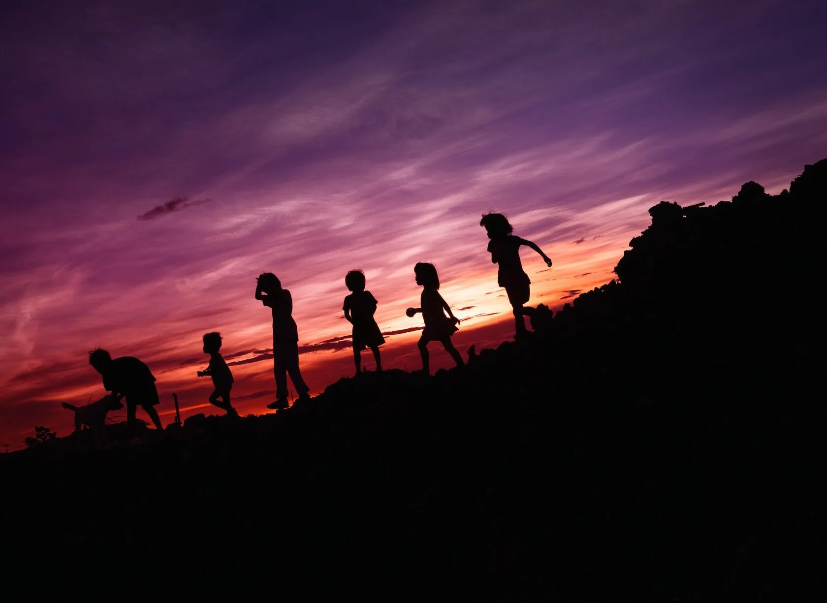 Silhouette d'enfants courant sur la colline